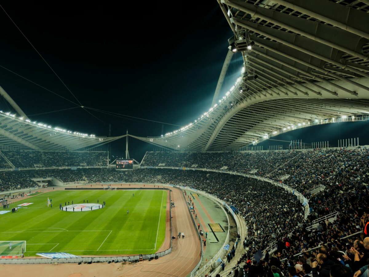 Stade de football rempli et illuminé lors d’un match en soirée